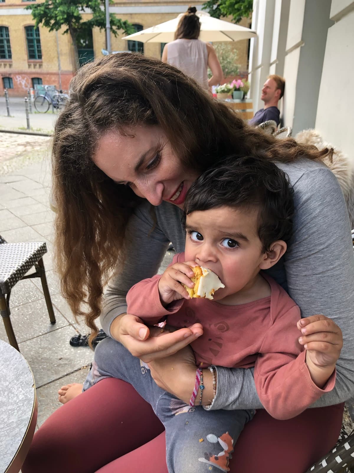A parent and child sharing a piece of cake outdoors