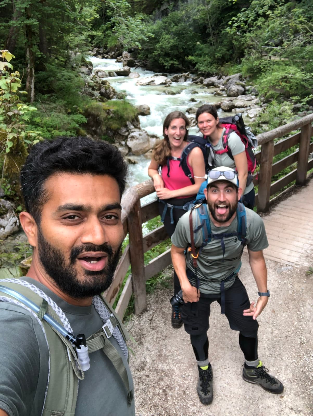 Friends with backpacks on a mountain path beside a stream